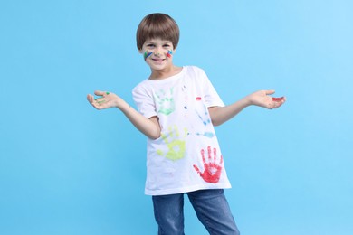 Photo of Portrait of smiling boy smeared in paint on light blue background