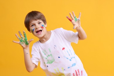 Photo of Portrait of funny boy smeared in paint on orange background