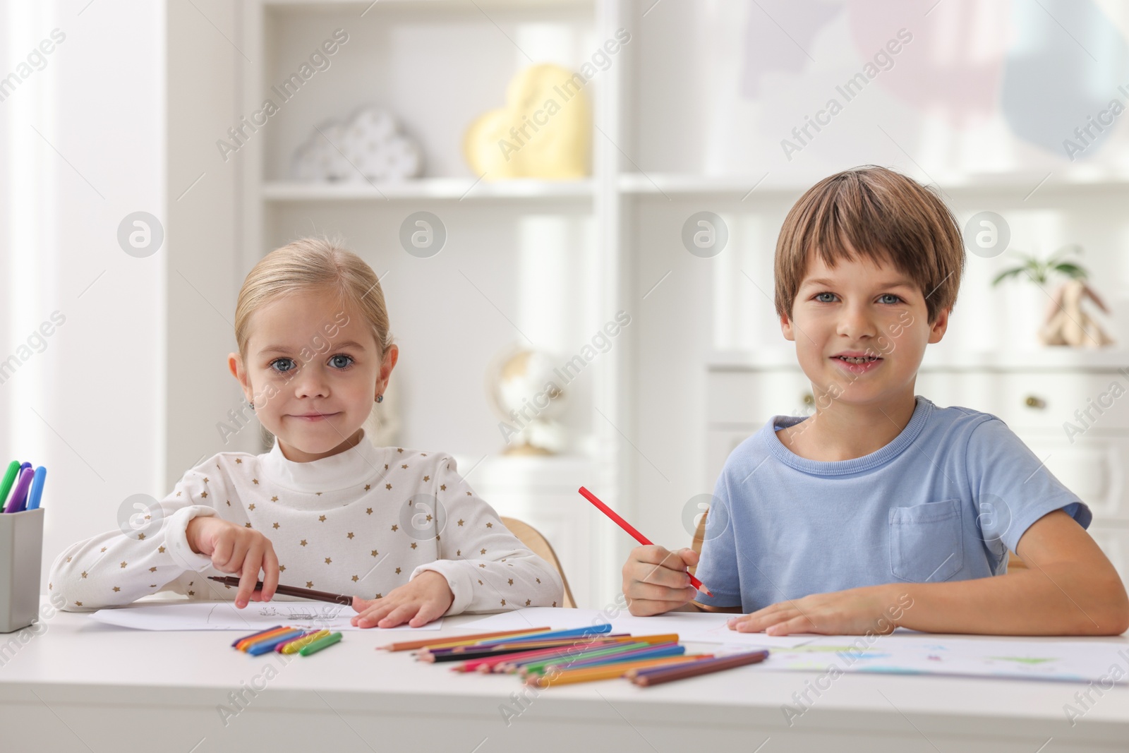 Photo of Cute children drawing at white table in kindergarten