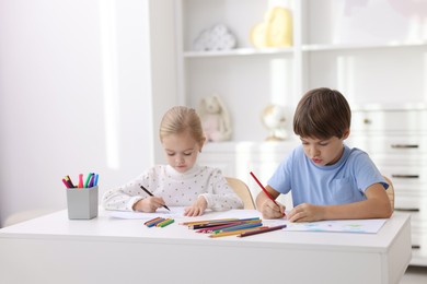 Photo of Cute children drawing at white table in kindergarten