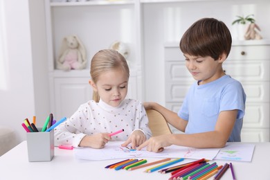 Photo of Cute children drawing at white table in kindergarten