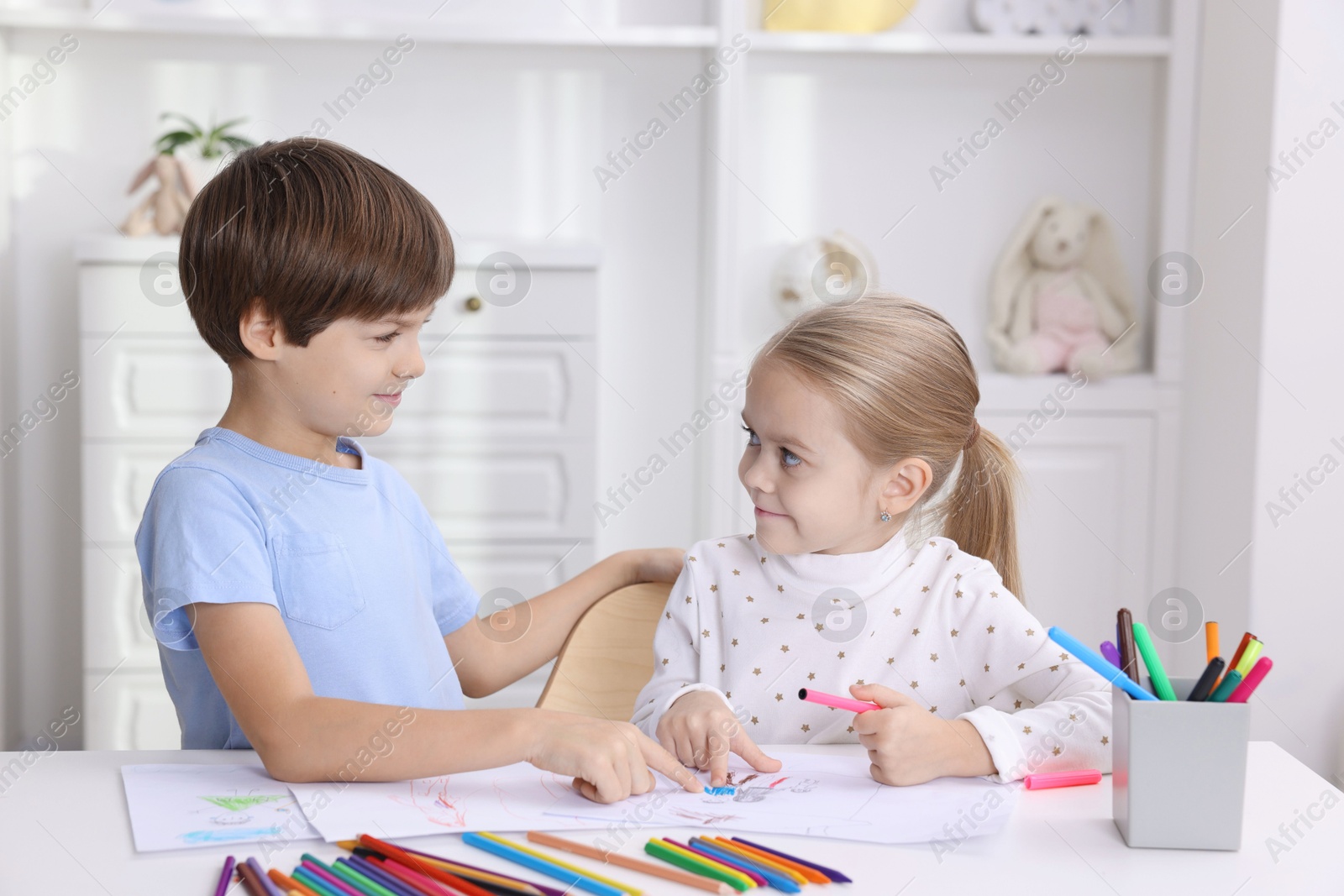 Photo of Cute children drawing at white table in kindergarten