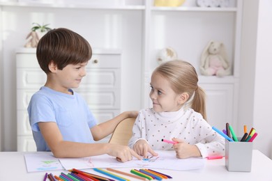 Photo of Cute children drawing at white table in kindergarten