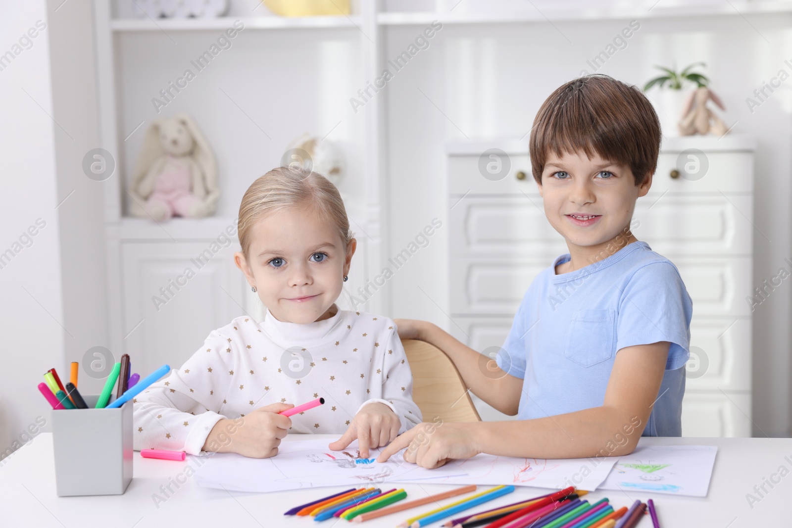 Photo of Cute children drawing at white table in kindergarten