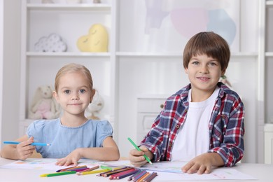 Photo of Cute children drawing at white table in kindergarten