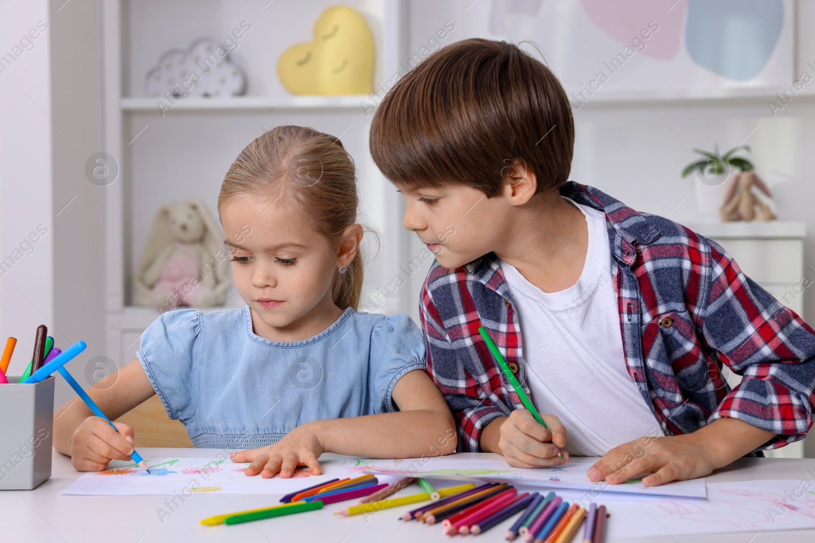 Photo of Cute children drawing at white table in kindergarten