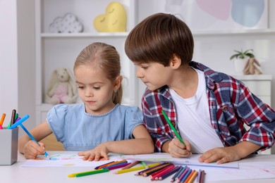 Photo of Cute children drawing at white table in kindergarten