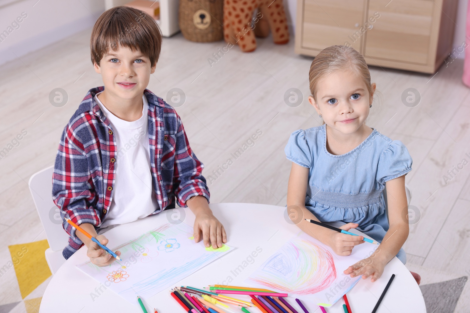 Photo of Cute children drawing at white table in kindergarten