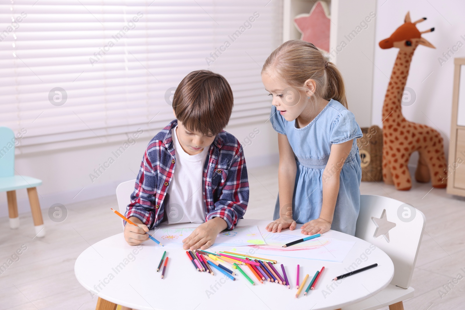 Photo of Cute children drawing at white table in kindergarten