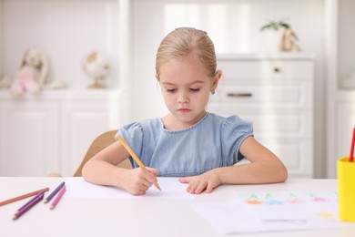 Photo of Cute girl drawing at white table in kindergarten