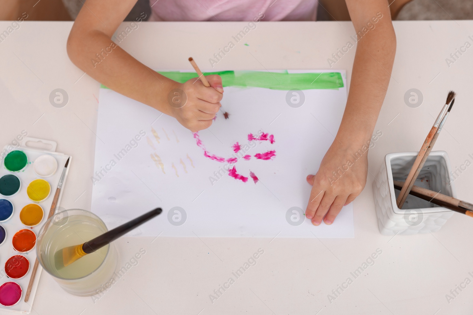 Photo of Girl drawing with paint at white table indoors, above view