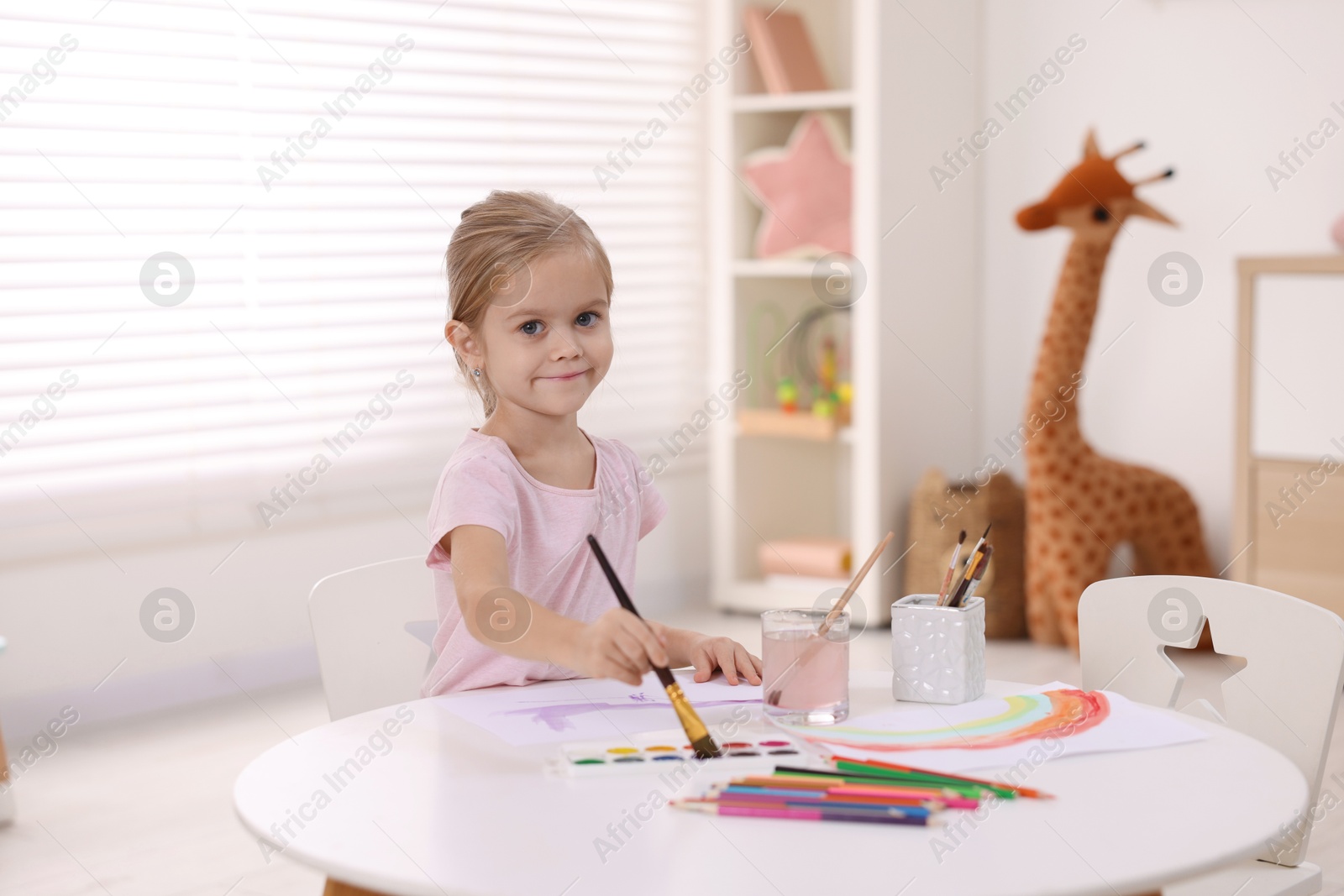 Photo of Cute girl drawing at white table in kindergarten