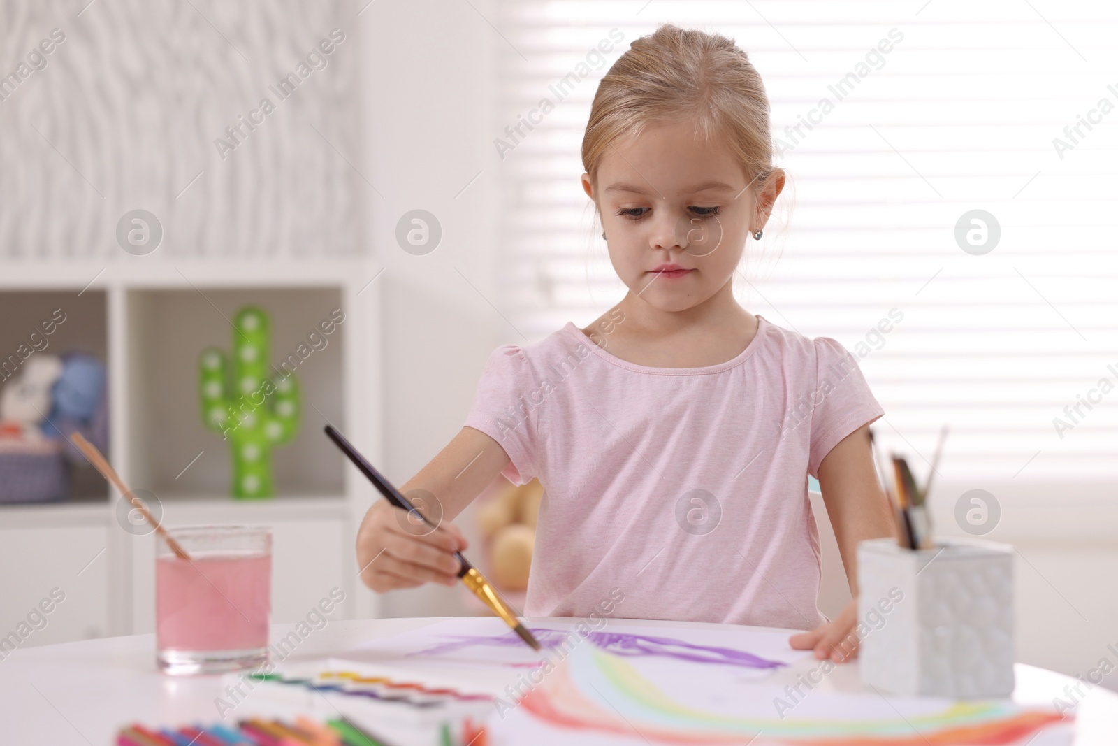 Photo of Cute girl drawing at white table in kindergarten