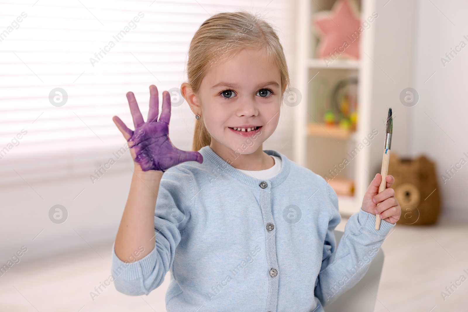 Photo of Happy girl drawing with palm in kindergarten