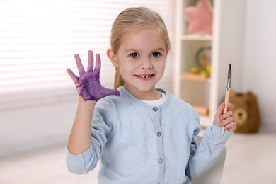 Photo of Happy girl drawing with palm in kindergarten