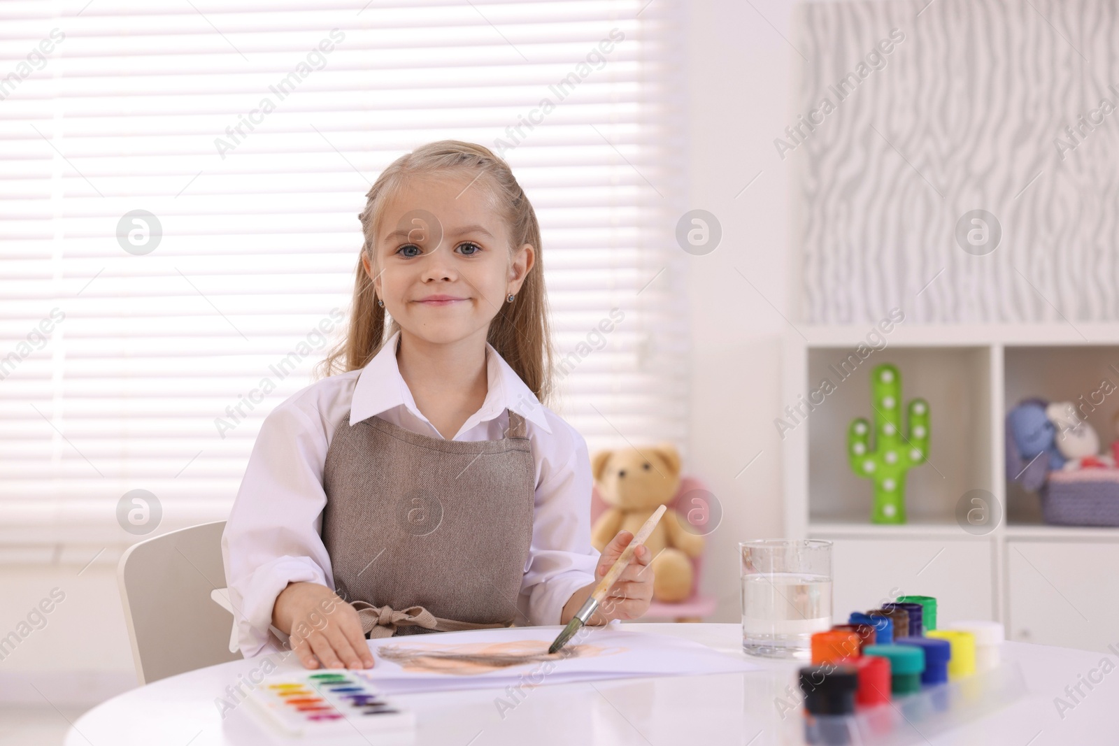 Photo of Cute girl drawing at white table in kindergarten