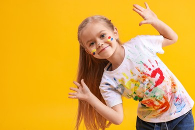 Photo of Portrait of funny girl smeared in paint on orange background. Space for text