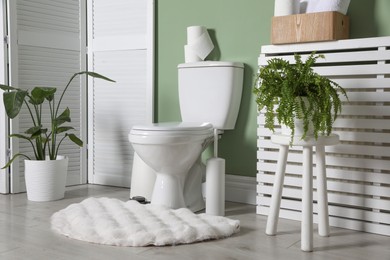 Photo of Folding screen, toilet bowl and houseplants in restroom