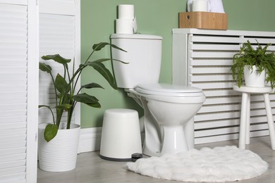 Photo of Folding screen, toilet bowl and houseplants in restroom