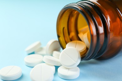 Photo of Bottle of antibiotic pills on light blue background, closeup