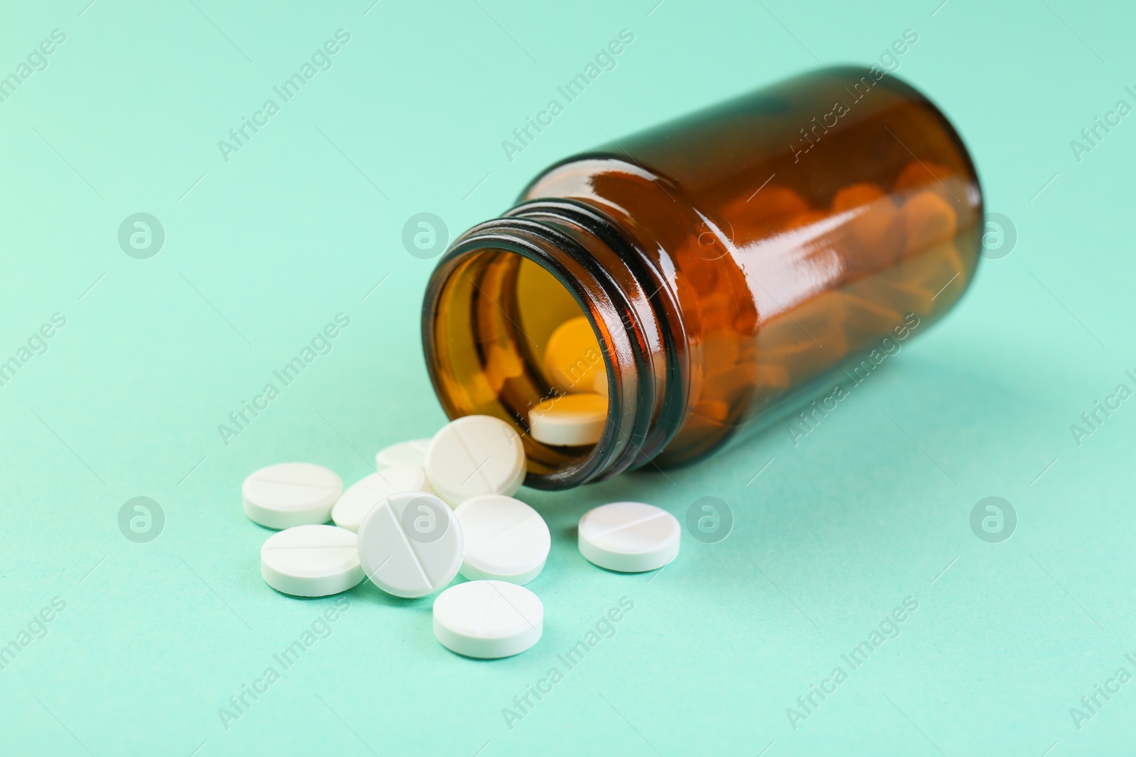 Photo of Bottle of antibiotic pills on turquoise background, closeup