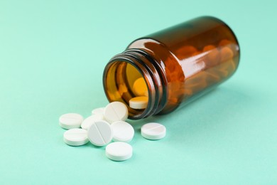 Photo of Bottle of antibiotic pills on turquoise background, closeup