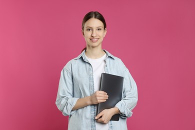 Photo of Portrait of smiling teenage girl with laptop on pink background