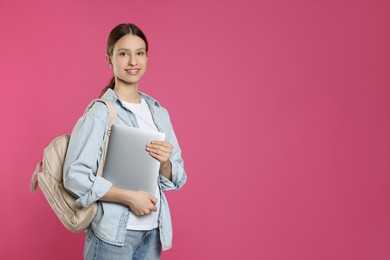 Photo of Portrait of smiling teenage girl with laptop on pink background. Space for text