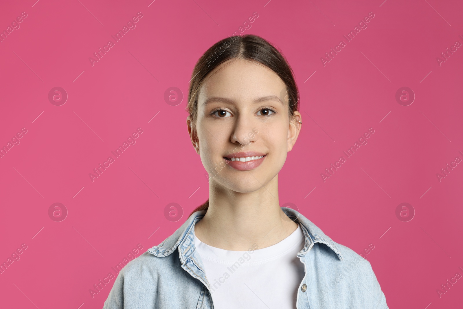 Photo of Portrait of smiling teenage girl on pink background