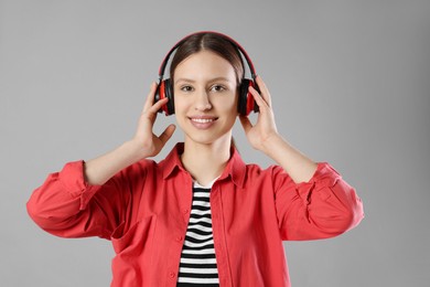 Photo of Portrait of smiling teenage girl in headphones listening to music on grey background