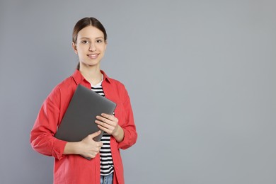 Photo of Portrait of smiling teenage girl with laptop on grey background. Space for text