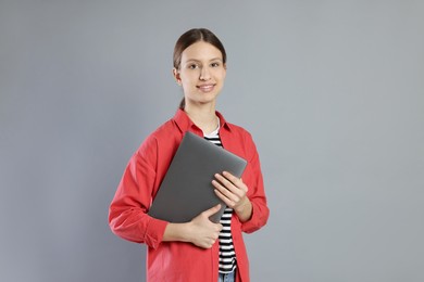 Photo of Portrait of smiling teenage girl with laptop on grey background