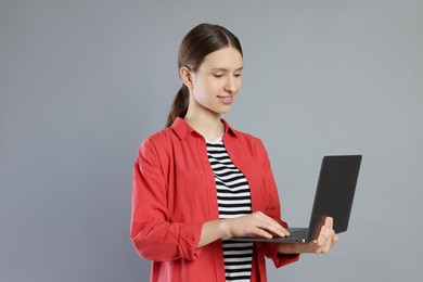 Photo of Portrait of smiling teenage girl with laptop on grey background