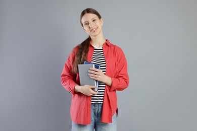 Photo of Portrait of smiling teenage girl with books on grey background