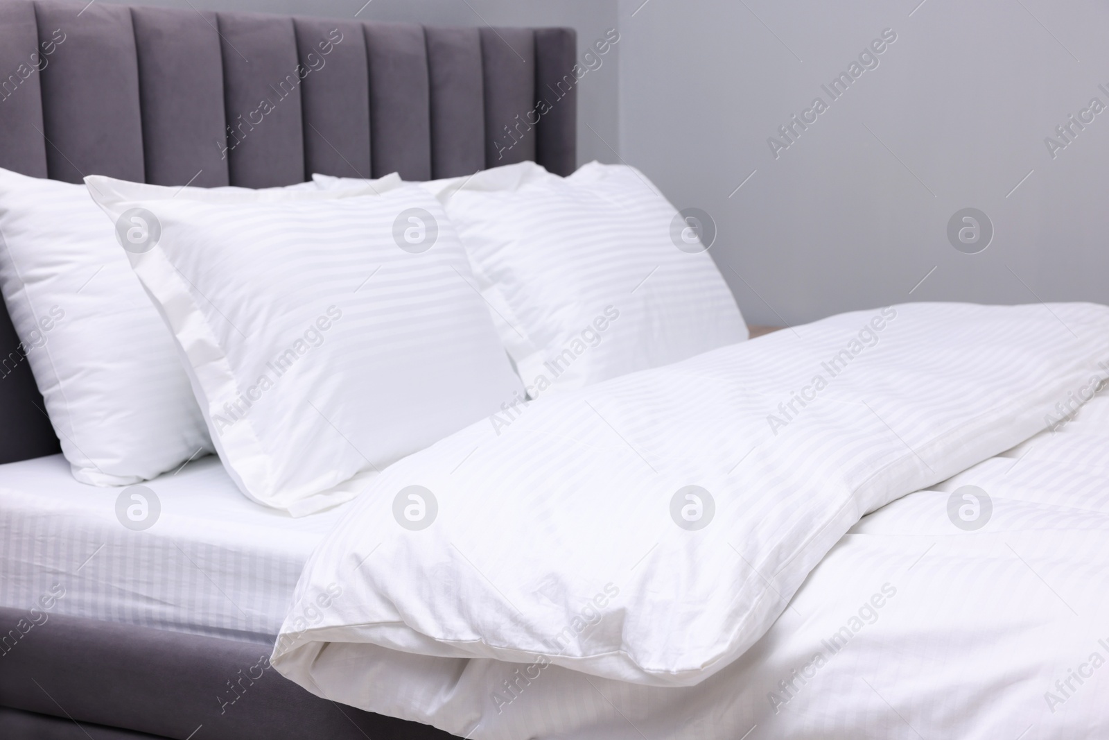 Photo of Bed with clean linens and pillows indoors