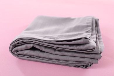 Photo of Stacked clean bed linens on pink background