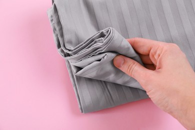 Photo of Woman with stacked bed linens on pink background, closeup