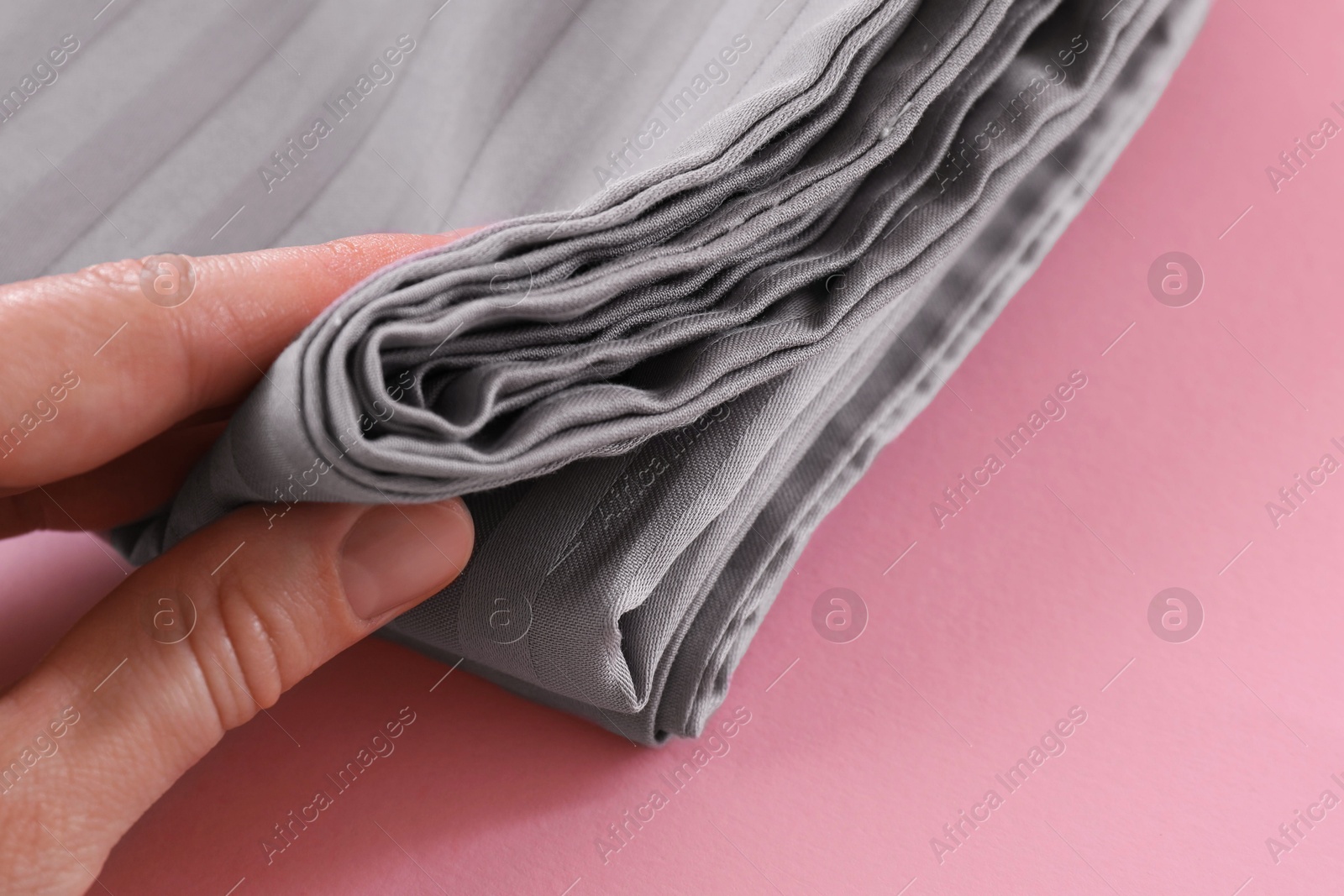 Photo of Woman with stacked bed linens on pink background, closeup