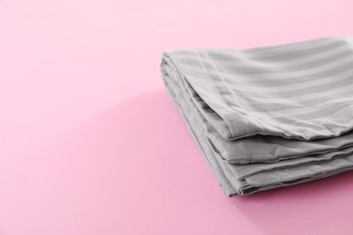 Photo of Stacked clean bed linens on pink background, space for text