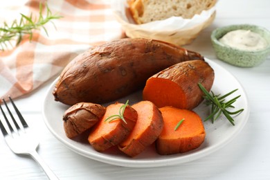 Tasty cooked sweet potatoes served with rosemary on white wooden table, closeup