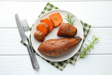 Photo of Tasty cooked sweet potatoes served with rosemary on white wooden table, top view