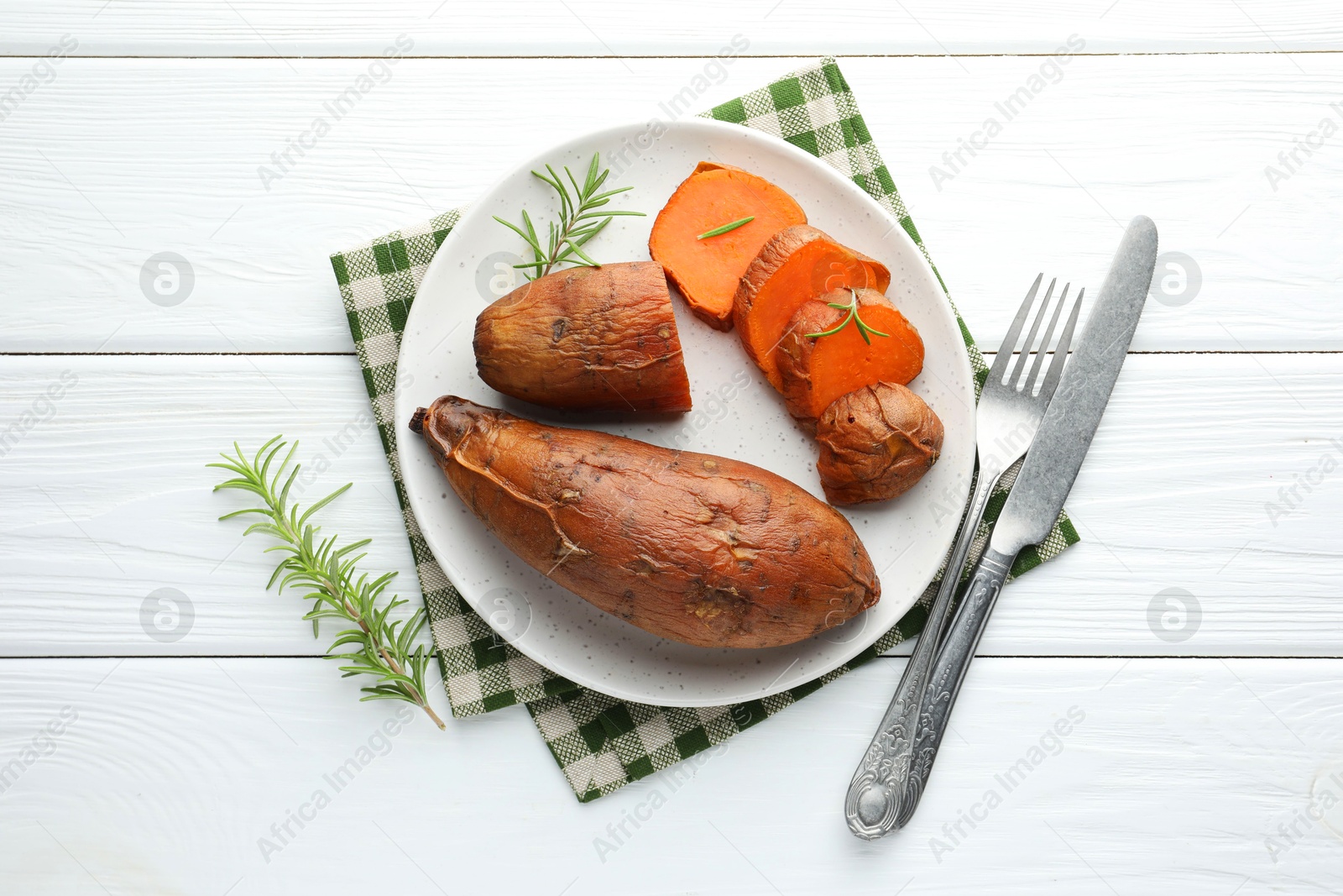 Photo of Tasty cooked sweet potatoes served with rosemary on white wooden table, top view