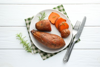 Tasty cooked sweet potatoes served with rosemary on white wooden table, top view