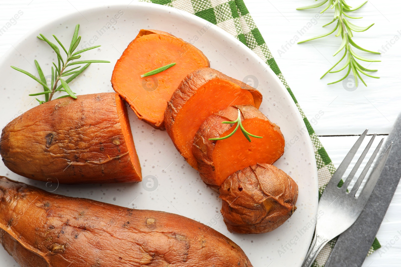 Photo of Tasty cooked sweet potatoes served with rosemary on white wooden table, top view