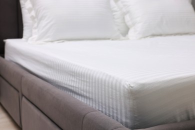 Photo of Bed with clean linens and pillows indoors, closeup