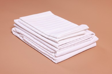 Photo of Stack of clean bed linens on beige background