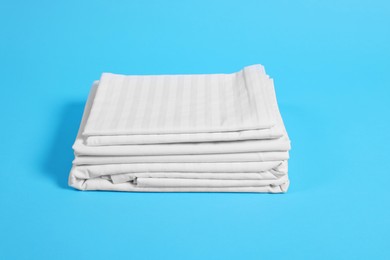 Photo of Stack of clean bed linens on light blue background