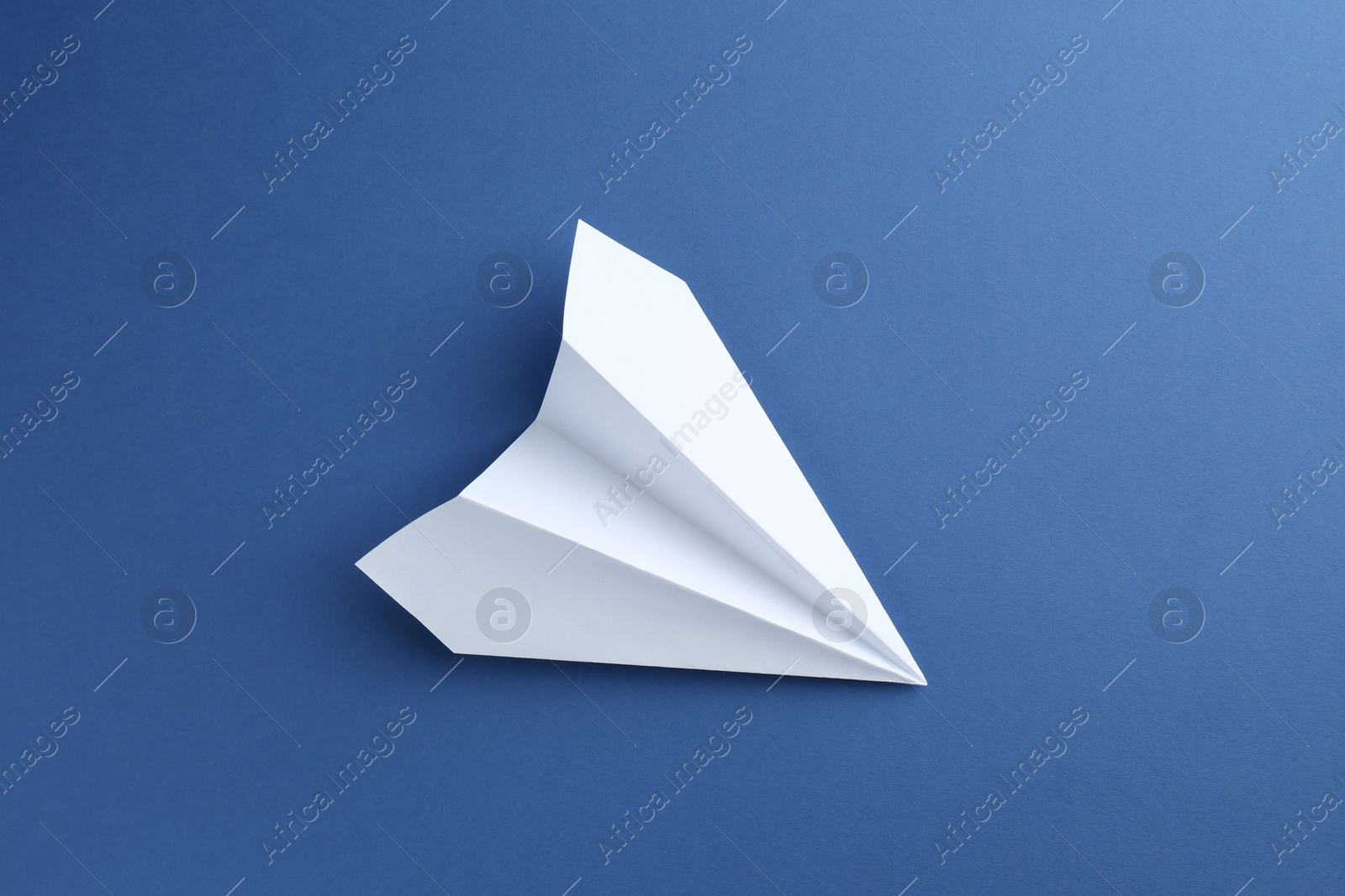 Photo of One handmade paper plane on blue background, top view