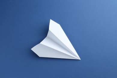 Photo of One handmade paper plane on blue background, top view