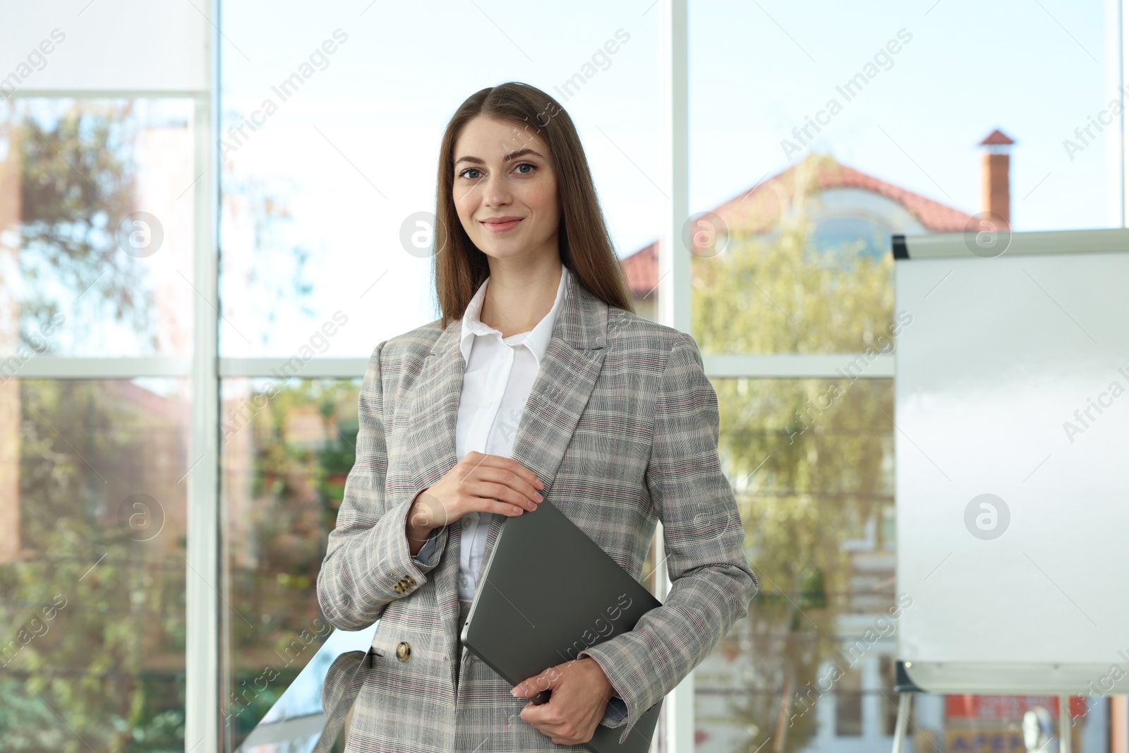 Photo of Portrait of young woman with laptop wearing stylish suit indoors